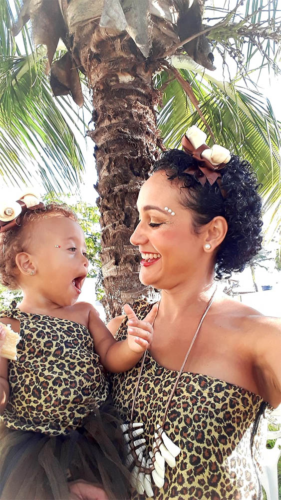 Lyana Cabral com sua filha no colo, uma olhando para a outra e sorrindo.