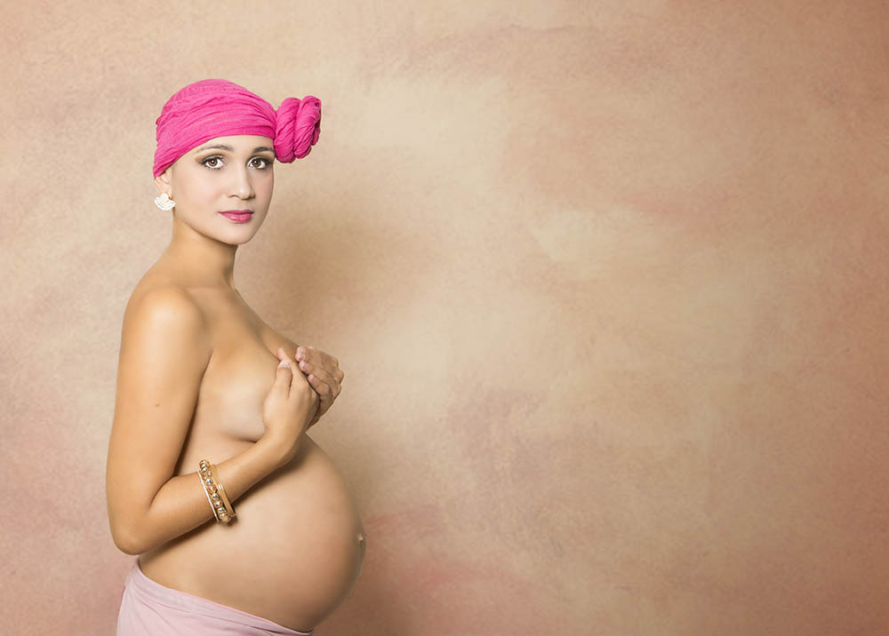 Lyana grávida usando lenço e tampando seios com as mãos em ensaio fotográfico.